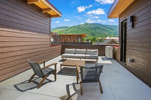 A wooden deck with a sofa, two chairs, and a table.