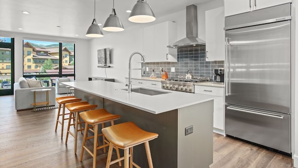 A modern kitchen with a large island, stainless steel appliances, and bar stools. - Urban Luxury - Rooftop Patio w/ Hot Tub, Perfect for 2 Families at Competitive Rates (Steamboat Springs)