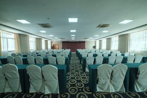 A conference room with rows of tables and chairs, a carpeted floor, and large windows on one side. - Xin Shun Hotel (Hongya)