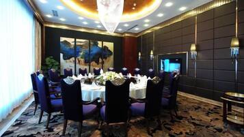 A dining area with a round table set for six, surrounded by chairs, in a room with a large painting on the wall and a chandelier.