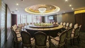 Un salón de conferencias con una mesa redonda, sillas y una araña.