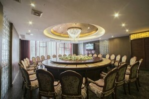 Ein Konferenzraum mit rundem Tisch, Stühlen und einer Kronleuchter.