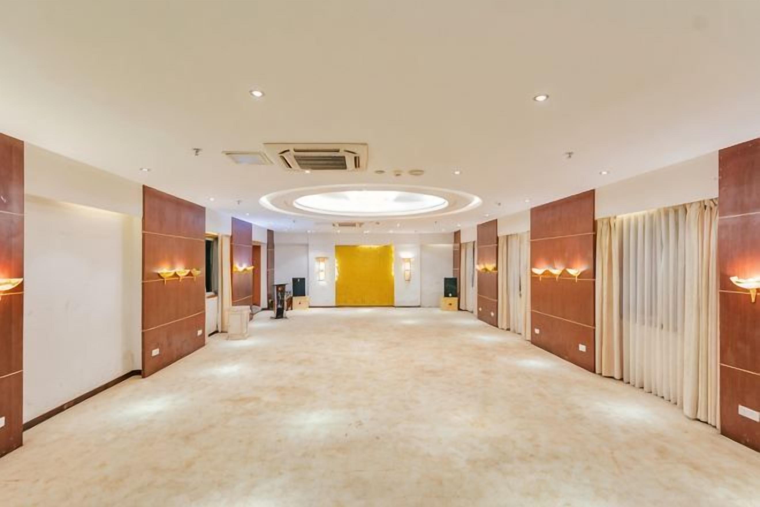 A hotel corridor with a carpeted floor, wooden panel walls, and recessed lighting.