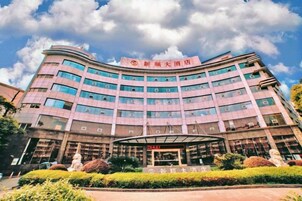 Un hotel de varios pisos con fachada curva, ventanas amplias y un área de entrada cubierta.