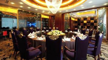 A formal dining room with round tables, purple chairs, and a chandelier.