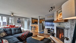 Una sala de estar moderna con chimenea, un comedor con sillas rojas y una cocina con armarios de madera.