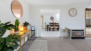 A modern living room with a wooden console table, a large mirror, a clock, and a fireplace.