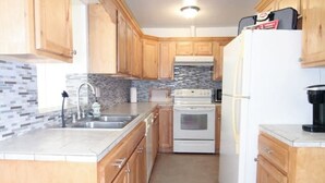 Una cocina con armarios de madera, un refrigerador blanco, una estufa y un salpicadero de azulejos.