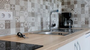 Una cocina con un salpicadero decorativo, una cafetera y un lavabo.