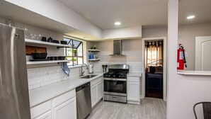 A compact kitchen with white cabinets, a stainless steel stove, and a dishwasher.