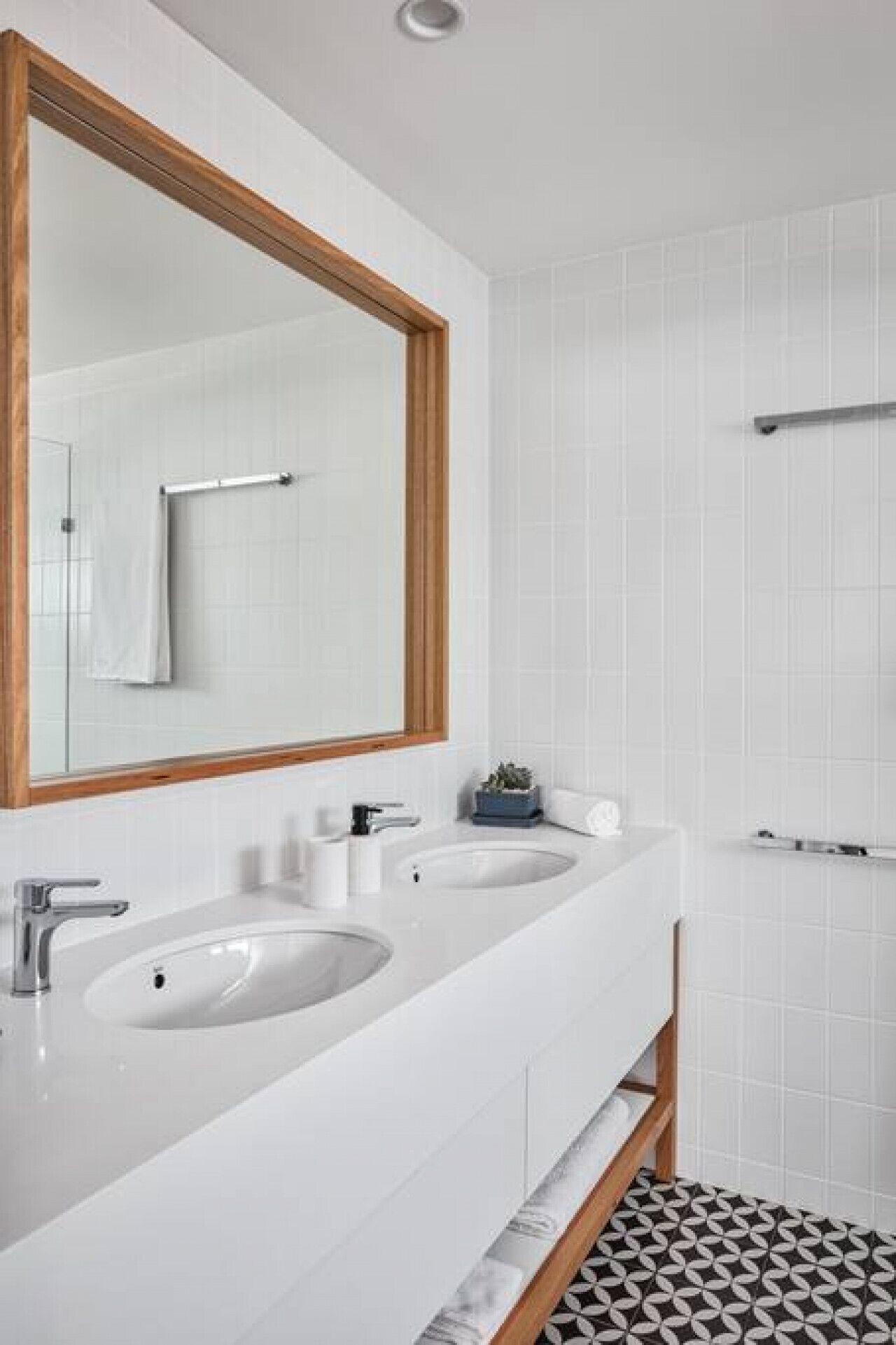 A bathroom with two sinks, a large mirror, and a shower area.