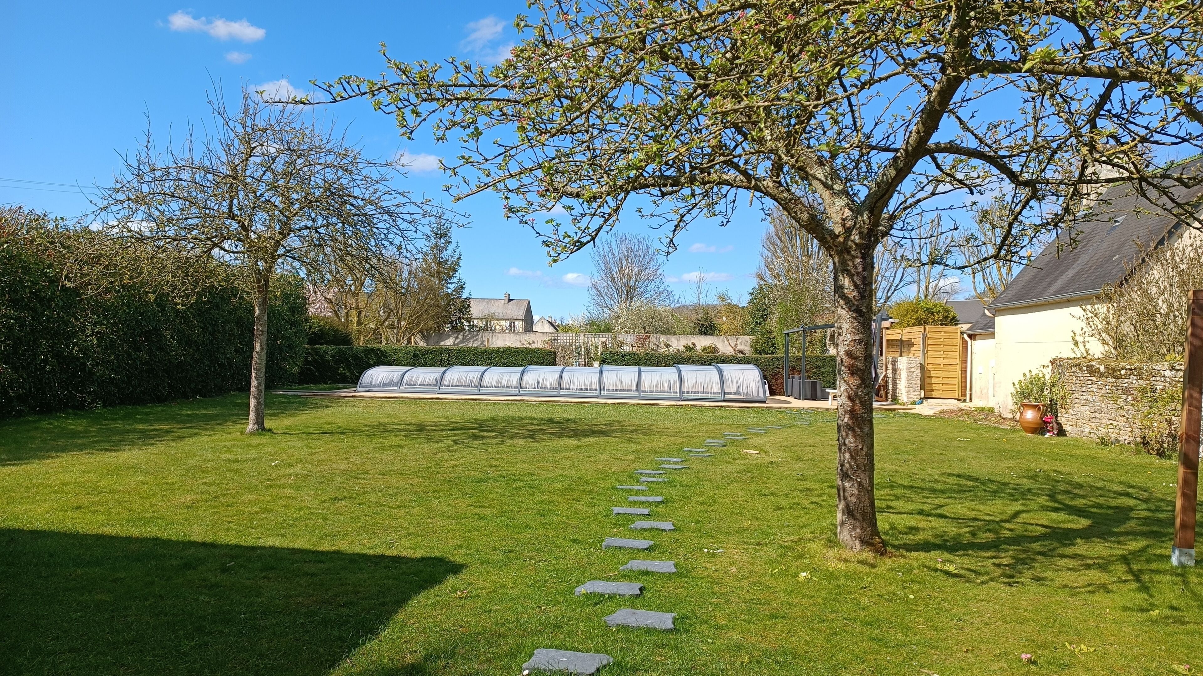 Un jardin bien entretenu, avec un chemin dégagé menant à une serre.
