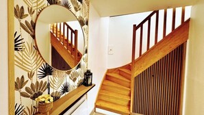 A staircase with wooden railings and a mirrored wall with a leaf pattern. - Gîte with swimming pool, Nordic bath, close to the landing beaches (le manoir)