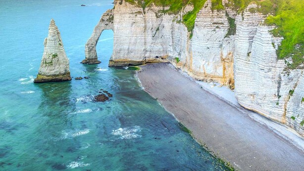 Eine Küstenlandschaft mit weißen Klippen, einem klaren blauen Meer und einem Sandstrand.