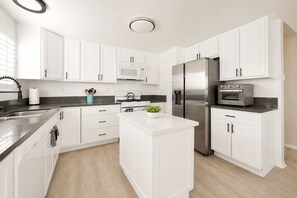 A modern kitchen with white cabinetry, stainless steel appliances, and a central island.