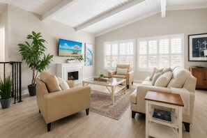 A spacious living room with a fireplace, comfortable seating, and large windows.