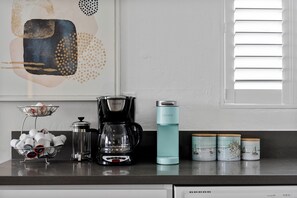 A kitchen counter with a coffee maker, a water bottle, and decorative jars.