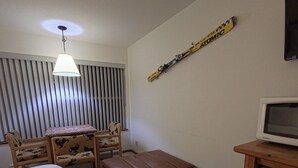 A compact room with a bed, a desk, a bench, and a TV. - Apex Inn 223 sleeps 5. Ski in/Ski out. Steps to Apex Resort Village (Penticton)