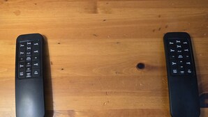 Two remote controls and one button remote on a wooden table. - Apex Inn 223 sleeps 5. Ski in/Ski out. Steps to Apex Resort Village (Penticton)