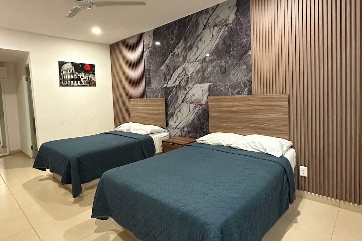 Habitación de hotel con dos camas, un muro de acento de mármol, paneles de madera, un ventilador de techo y un cartel del edificio del Capitolio.
