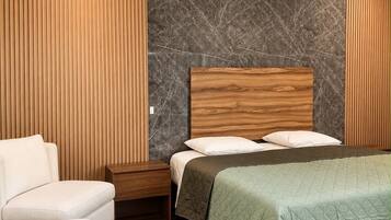 A bedroom with a bed, a nightstand, a chair, and a ceiling fan.