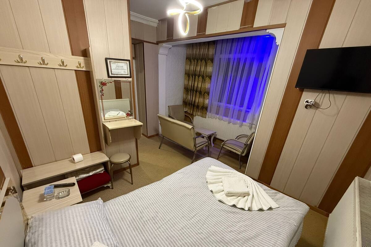 A hotel room with a bed, a desk, a chair, a vanity with a mirror, and a television.
