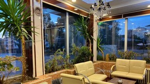 A well-lit indoor area with large windows, comfortable seating, and indoor plants. - Otel Büyük Doğu  (Erzurum)
