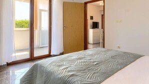 Quarto com cama, porta de vidro deslizante para uma varanda e guarda-roupa de madeira.