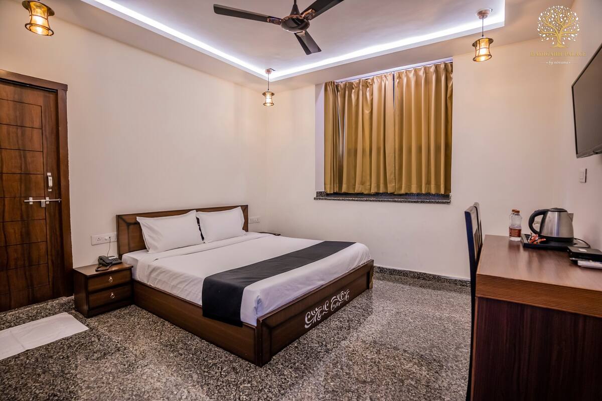 A bedroom with a bed, wooden nightstand, desk, and a ceiling fan.