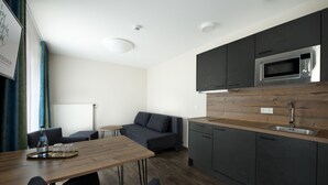 A modern kitchen with dark cabinets, a stainless steel microwave, and a wooden countertop. - Hotel Zum Grünen Baum (Ellwangen)