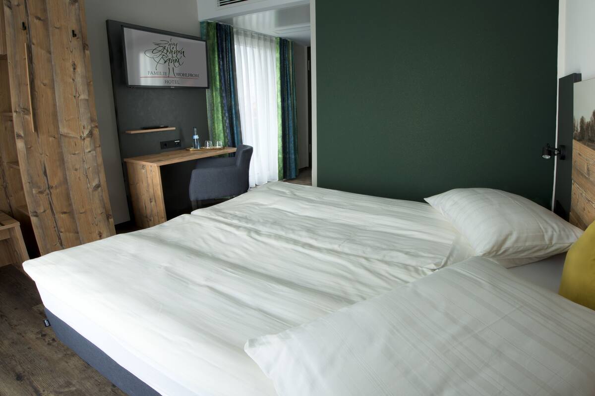 A hotel room with a large bed, a desk, and a TV mounted on the wall.