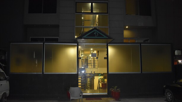 A building with a glass facade, a visible entrance, and a chair outside. - PINE VIEW HOTEL (Mekhtar)