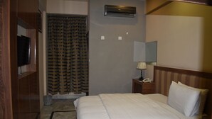 A hotel room with a bed, a nightstand with a lamp, a telephone, an air conditioning unit, and a shower curtain. - PINE VIEW HOTEL (Mekhtar)