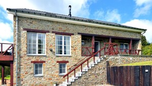 A stone building with a staircase, large windows, and a wooden deck. - Perfect Holiday Home in Trou de Bra with private garden and mountain views (Trou de bra)