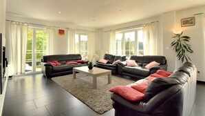 A spacious living room with two black leather sofas, a wooden coffee table, and a large window with curtains. - Perfect Holiday Home in Trou de Bra with private garden and mountain views (Trou de bra)