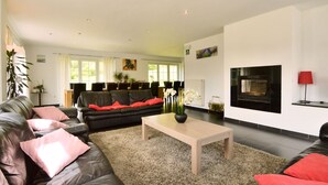 A modern living room with a fireplace, leather sofas, and a coffee table. - Perfect Holiday Home in Trou de Bra with private garden and mountain views (Trou de bra)