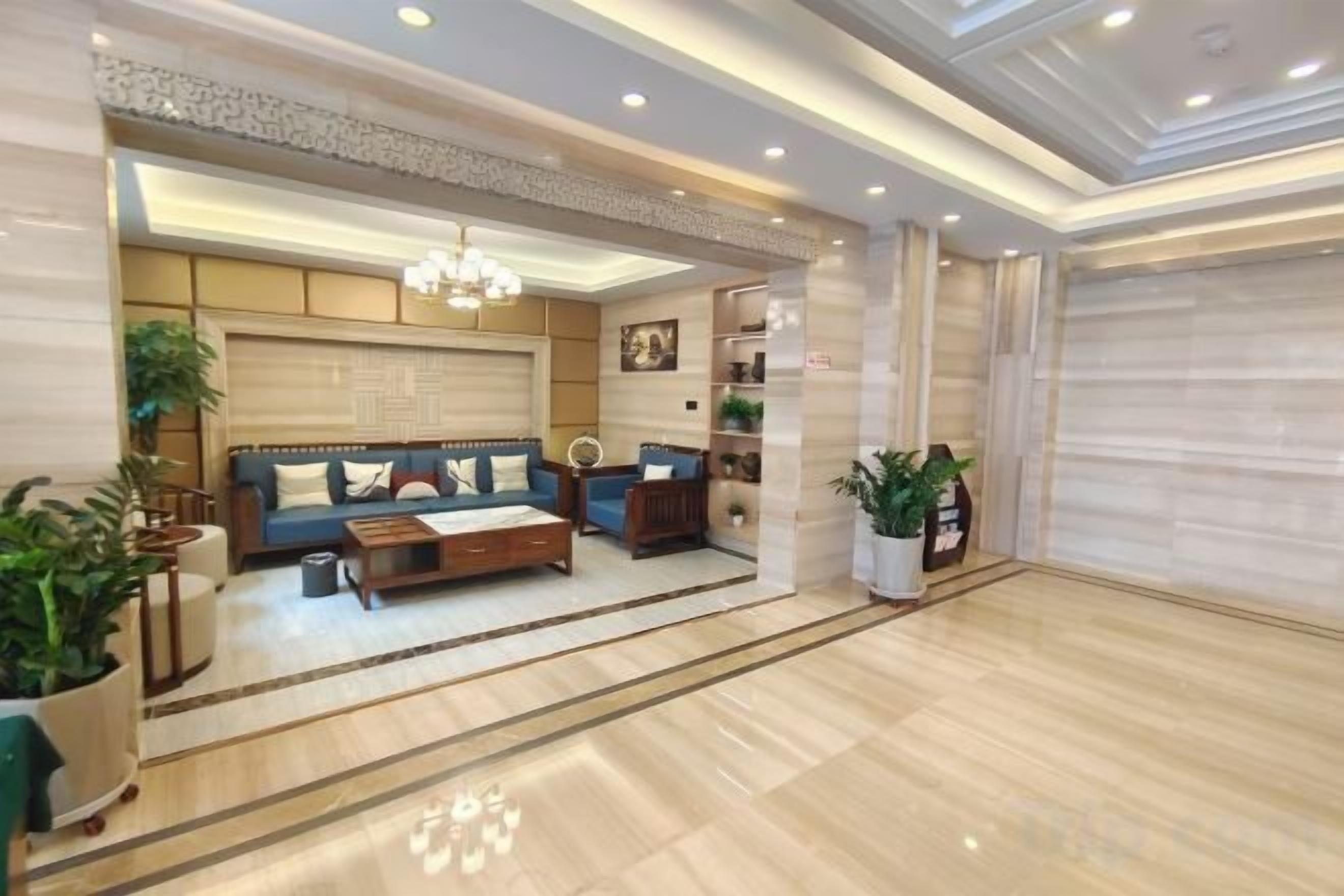 A spacious lobby with a sofa set, a coffee table, and a chandelier.