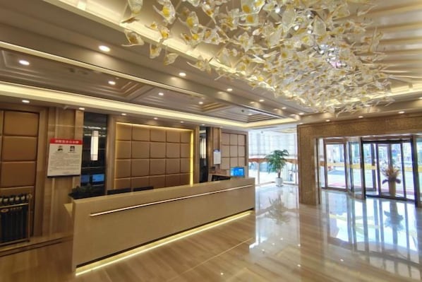 A hotel reception area with a modern design, a reception desk, and a large glass door leading outside. - Zengdu Hotel (Suizhou)