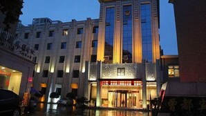 Un hôtel à plusieurs étages, doté d’une entrée imposante et d’une bande verticale de fenêtres sur la façade.