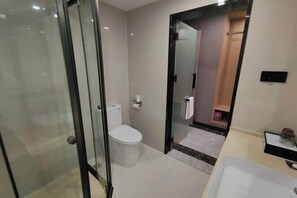 A modern bathroom with a glass shower enclosure, a toilet, and a sink with a mirror. - Zengdu Hotel (Suizhou)