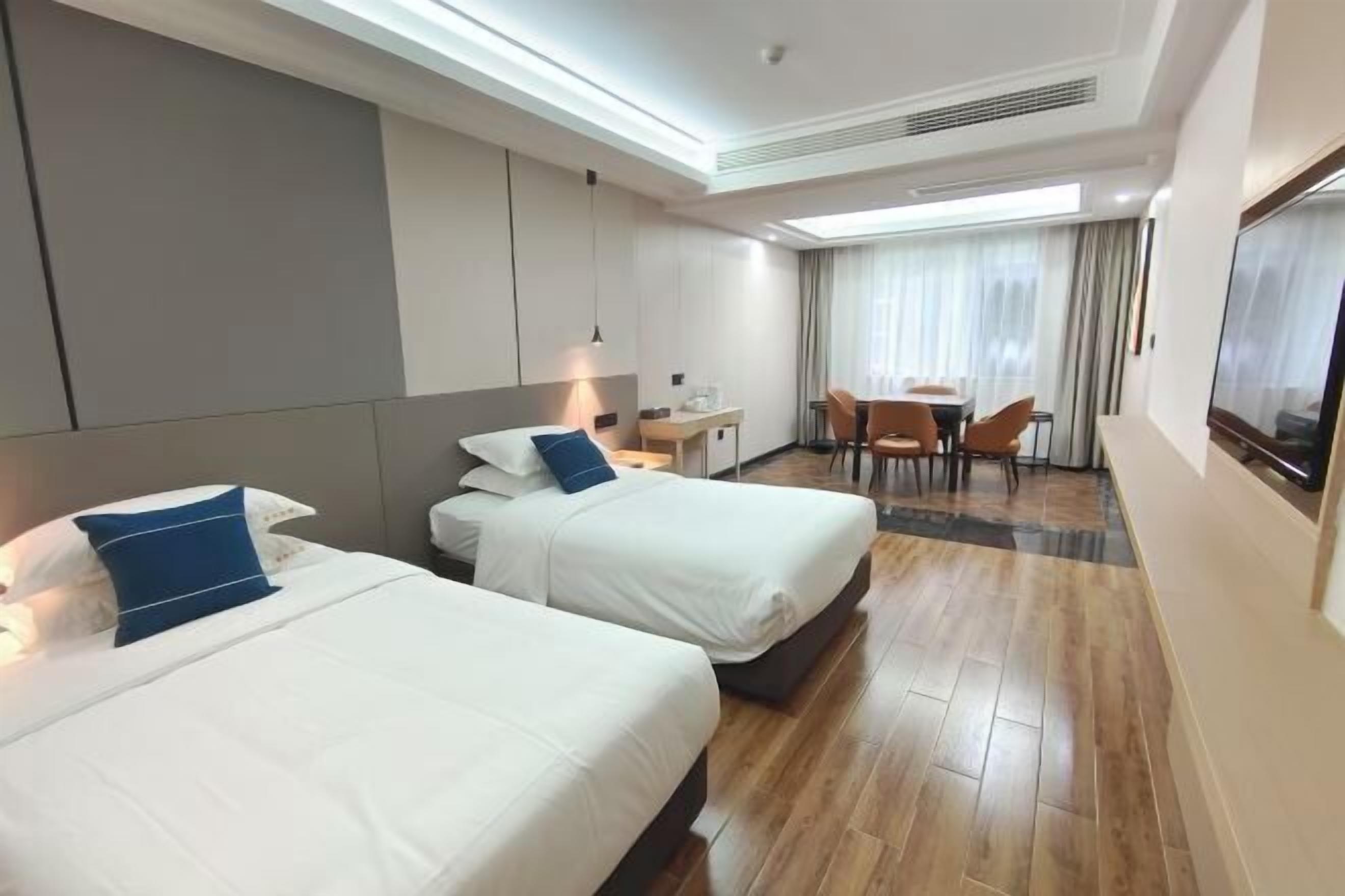 Una habitación de hotel con dos camas, un escritorio, una silla y un televisor.