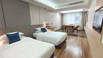 Una habitación de hotel con dos camas, un escritorio, una silla y un televisor.