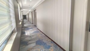 Un largo pasillo con alfombra estampada, paredes blancas y puertas que dan a habitaciones.