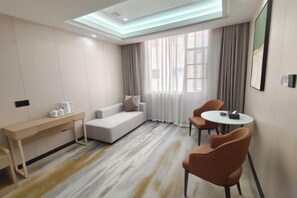 A modern hotel room with a sofa, two chairs, a small table, and a desk. - Zengdu Hotel (Suizhou)