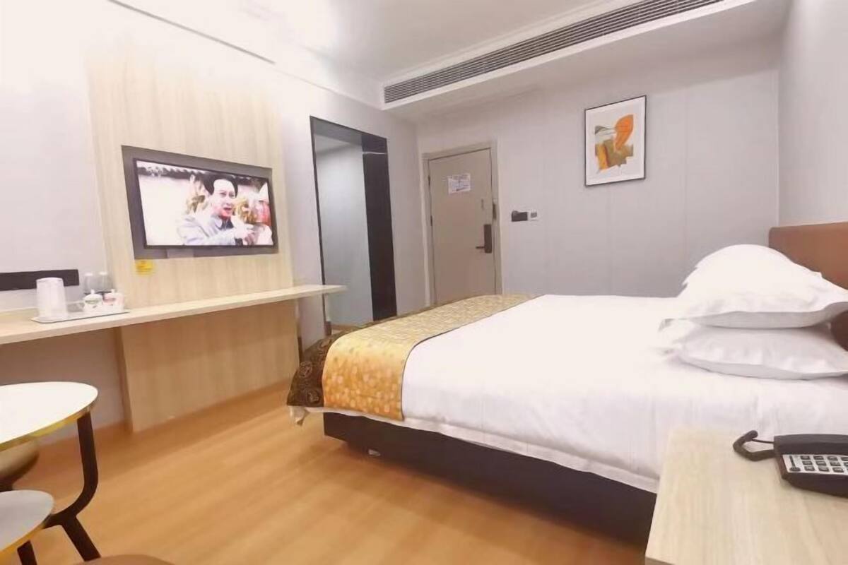 A hotel room with a bed, a desk, a chair, a television, and a phone.