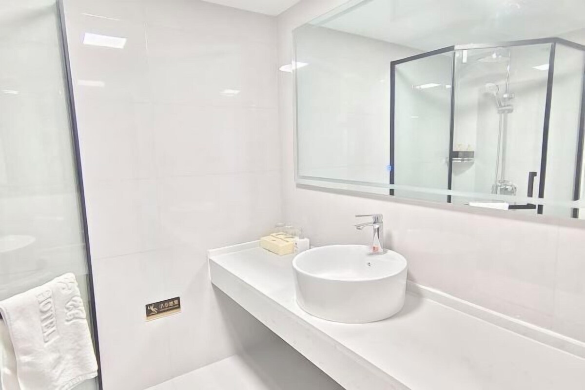 A modern bathroom with a glass shower enclosure, a white sink, and a large mirror.