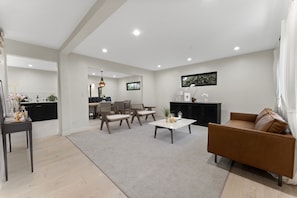 Un salon moderne avec un canapé marron, une table basse et un coin repas avec des chaises.