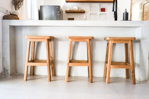 A kitchen with three wooden stools, a white countertop, and a stainless steel appliance. - Sun & Moon Villa (Canggu)