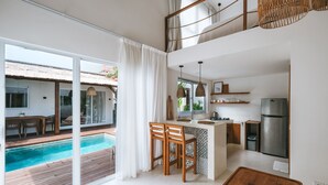 A modern kitchen with a large island, a dining area with a pool view, and a spacious living area with a balcony. - Sun & Moon Villa (Canggu)