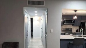 A modern kitchen with a central island, a dining area with bar stools, and a hallway leading to bedrooms. - Eastside 3 bed 2 bath, King en suite & fast Wifi (El Paso)